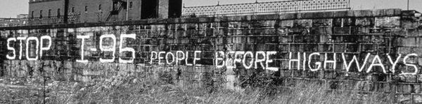 Spray paint on a wall, "Stop I-95 People Before Highways".