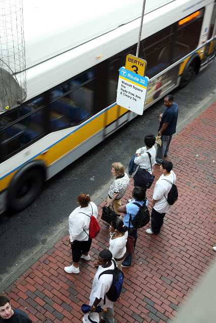 Bus passengers wait to board.