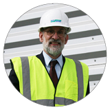 Photograph of article author William S. Kuttner, an older white man with a beard and glasses, wearing a yellow reflective vest and hardhat.